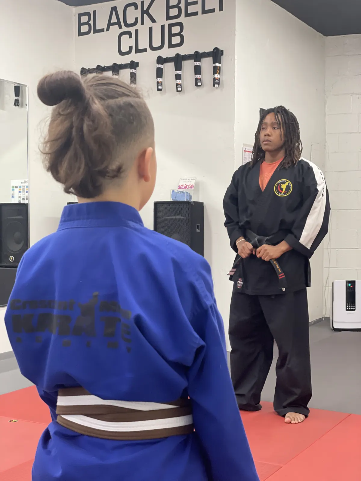 A student standing at attention facing an instructor before class begins.